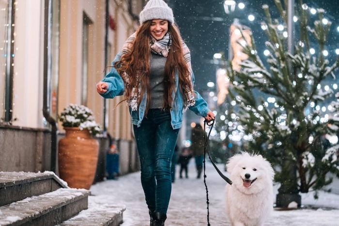 女性と冬の街を散歩している犬