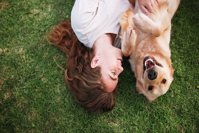 女性と一緒に寝転ぶ犬