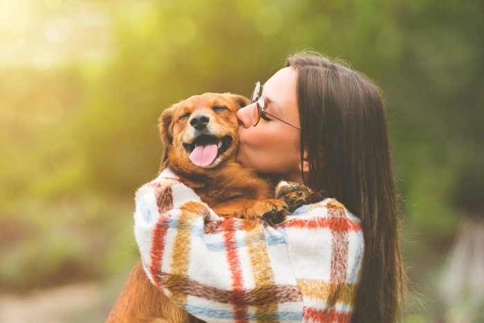 女性に抱っこされている犬