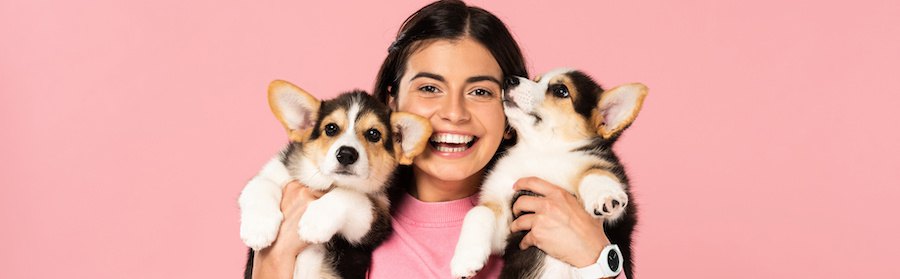 両手に二匹の子犬を抱えて笑う少女