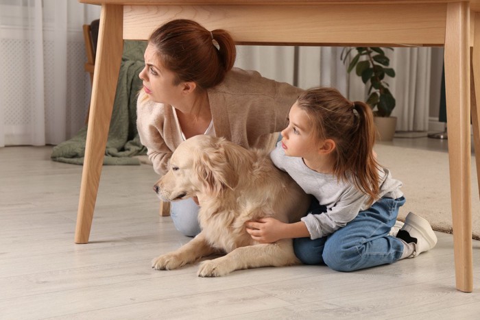 机の下に避難する母子と犬