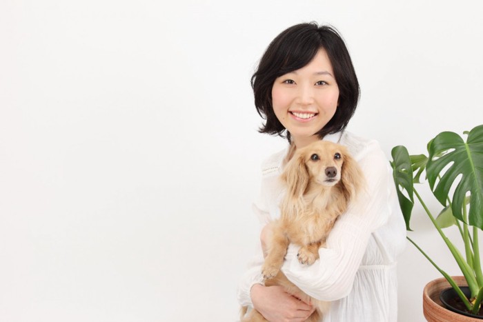 小型犬を抱く女性