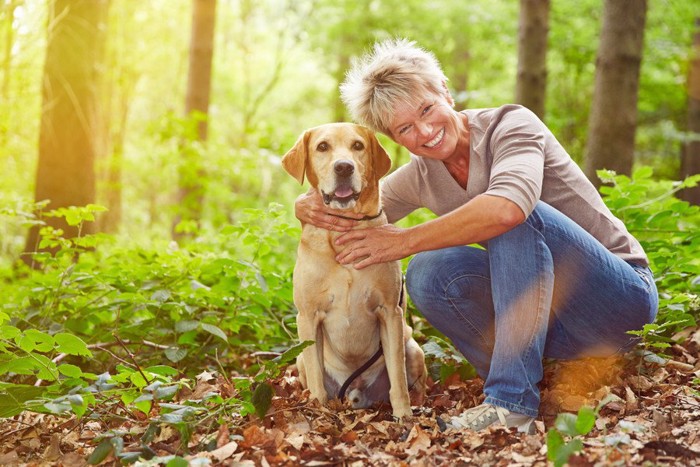 笑顔の女性と共に並ぶ犬