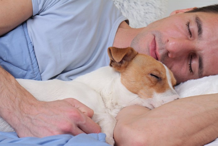 犬と添い寝する男性