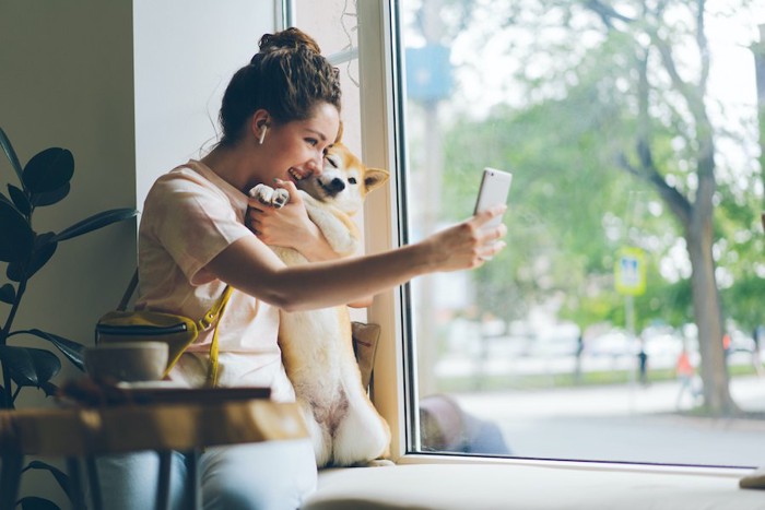 携帯で愛犬と自撮りする女性