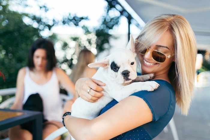 女性に抱っこされている犬