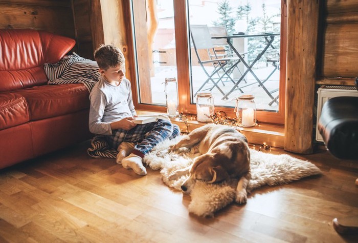 眠る犬の隣で本を読む男の子