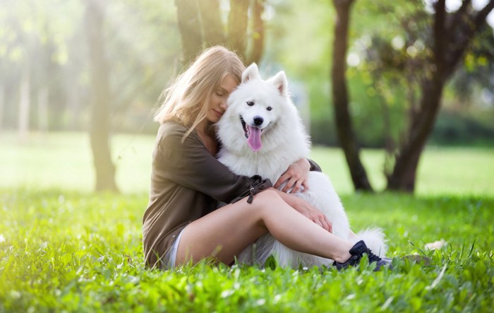 芝生の上で大型犬を抱きしめる女性