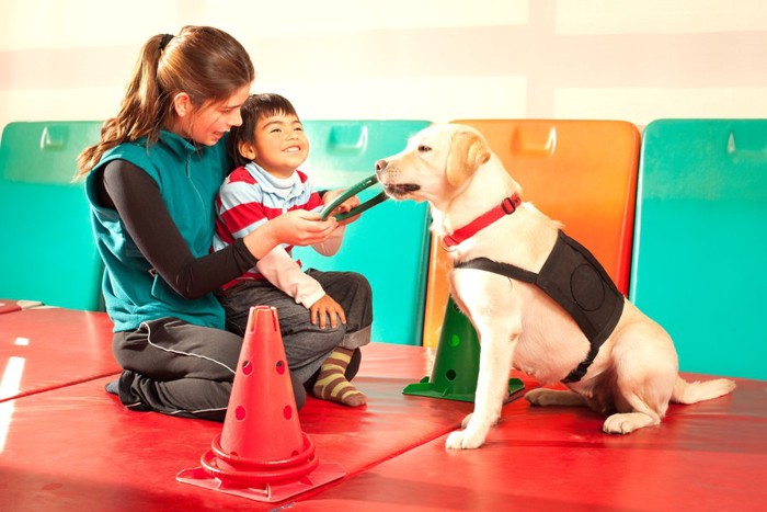 セラピー犬と遊ぶ女性と子供