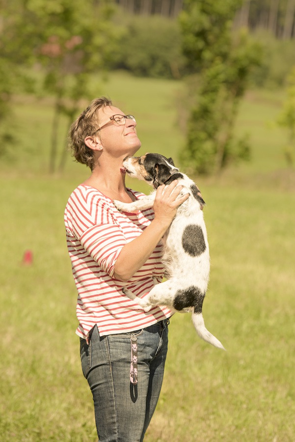 犬の脇を持って抱き上げる女性