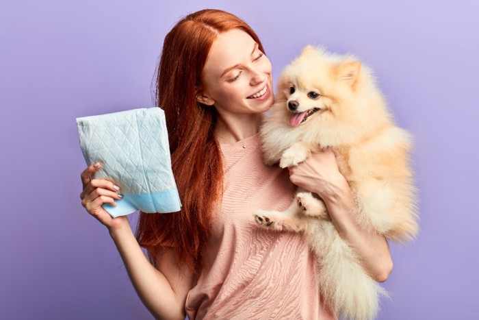 シートを持つ女性と犬と