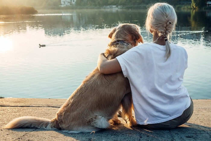 肩を寄せ合う女性と犬の後ろ姿