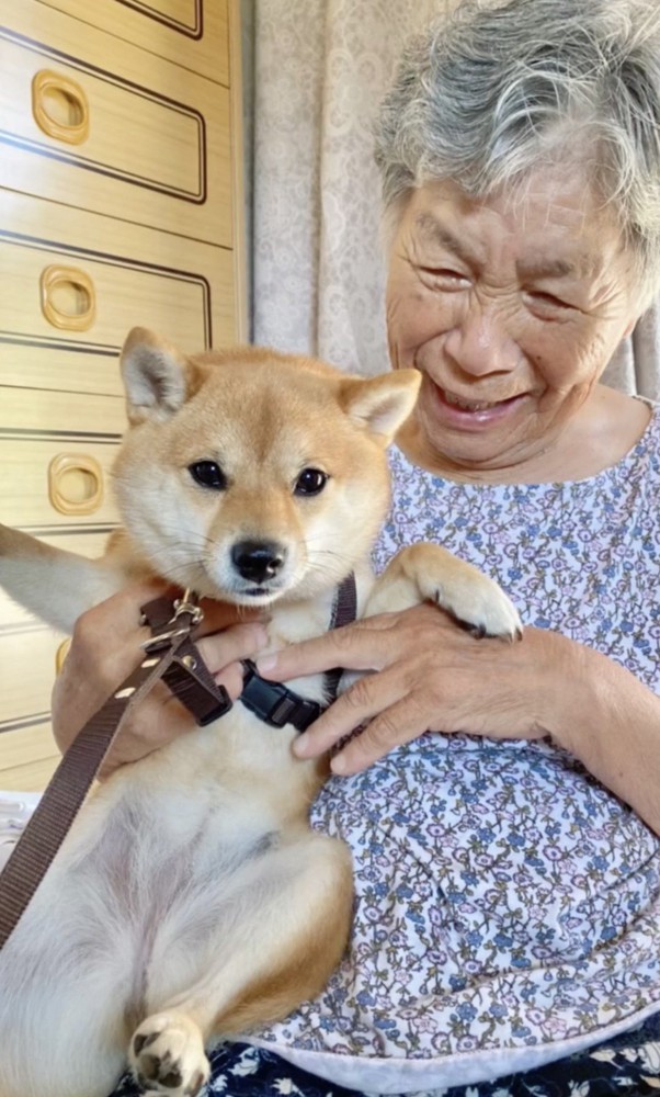 犬を抱いてほほえむ人