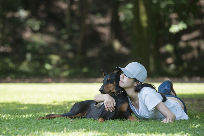 木陰で休憩する犬と女性