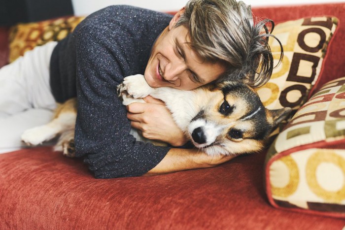 横になった犬に乗って抱きしめる男性