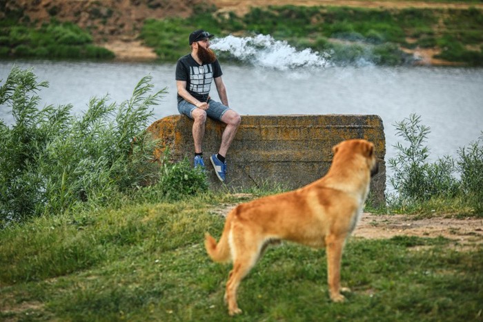 たばこを吸う男性とそれを見る犬