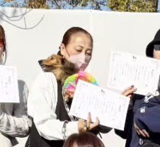 犬を抱っこしながら表彰状を持って記念撮影する飼い主