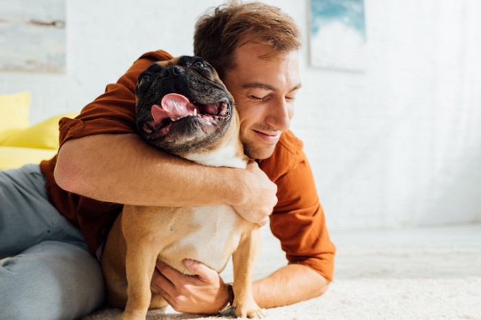 男性にハグされている犬