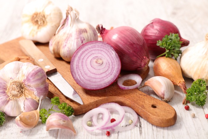 まな板の上に置かれた生の玉ねぎやにんにく