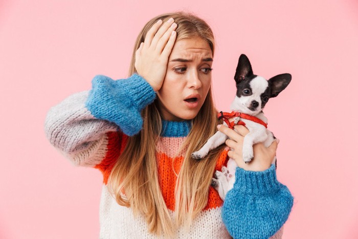 頭を抱える女性と犬