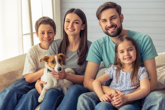 ソファーに座る家族と子犬