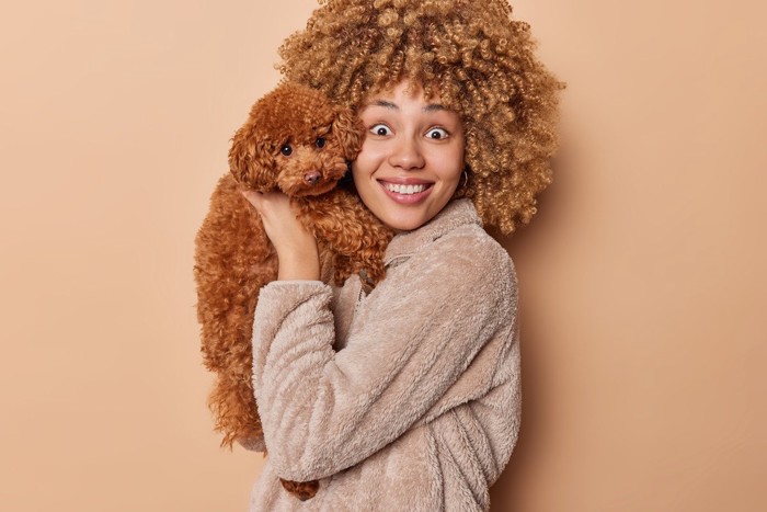 困った顔の犬を抱いて驚かす女性