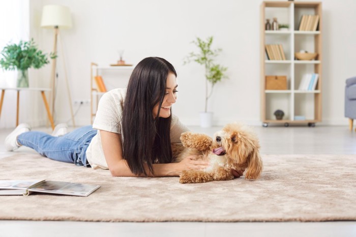 寝転びながら犬と遊ぶ女性