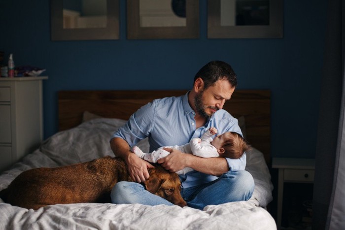 赤ちゃんを抱く男性とそばにいる犬