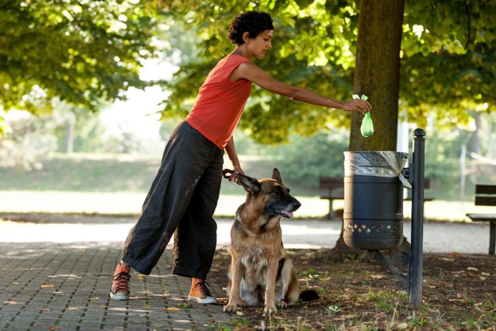 愛犬の後片付けをしましょうのボードを持つ女性犬のフンを捨てている女性