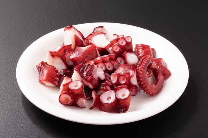 お皿の上にのった茹でてぶつ切りにされたタコ