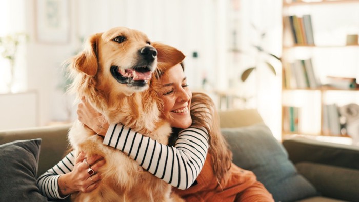 ソファで犬を抱きしめる女性