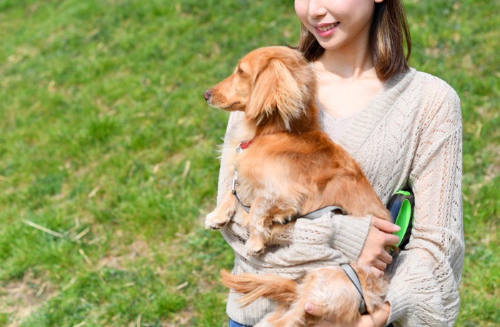 屋外で犬を抱っこする女性