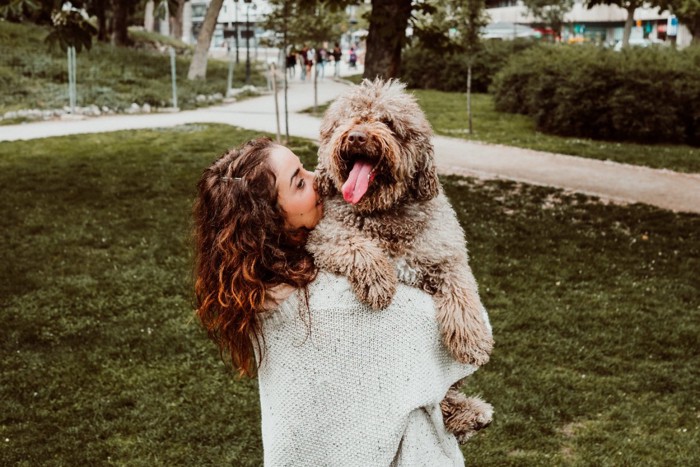 縦に犬を抱っこする女性