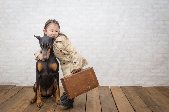 旅支度をした女の子と座る犬