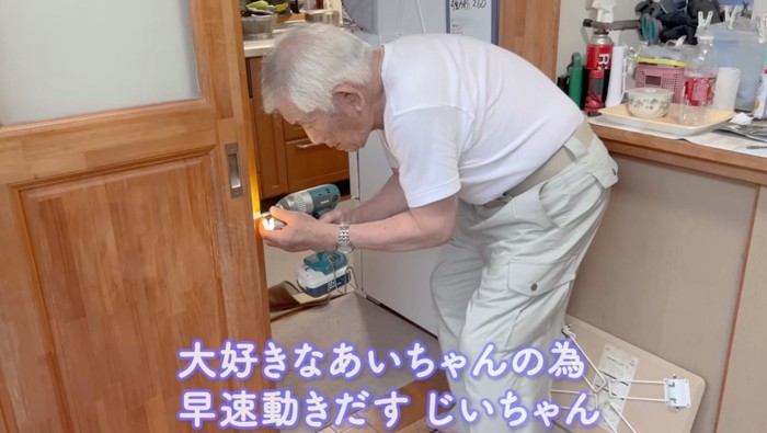 工具を持って壁に穴を開けるおじいちゃん
