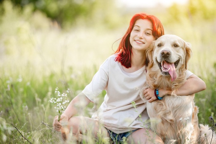 芝生の上で肩をくむ女性と犬