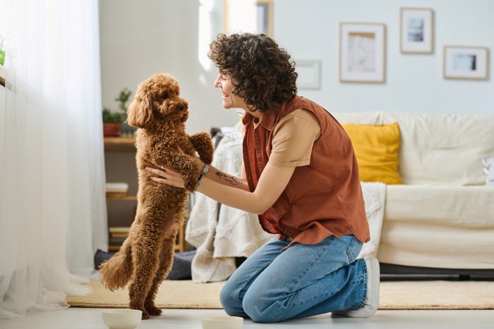 女性に上半身を抱き上げられている犬