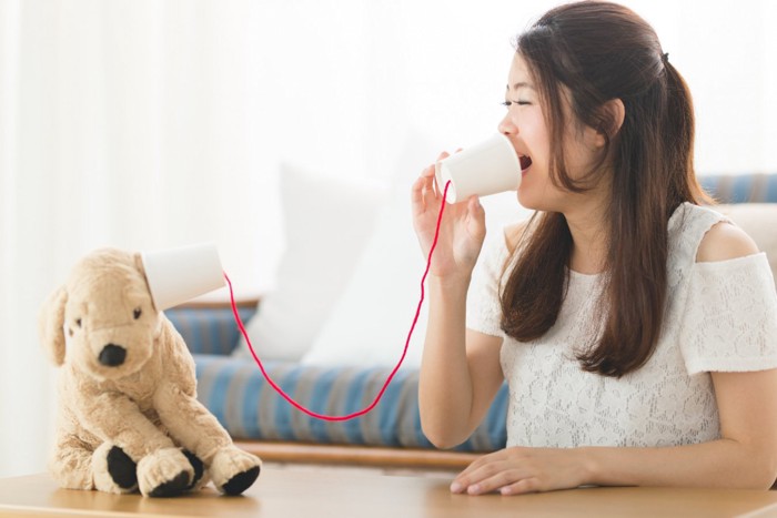 わんこのぬいぐるみと糸電話する女性