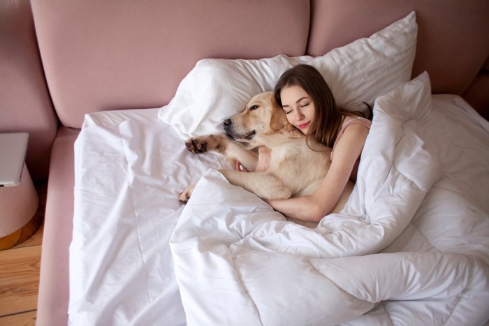 大型犬に抱きついて寝る女性