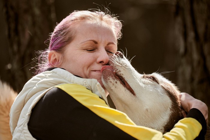 大型犬に口を舐められる女性