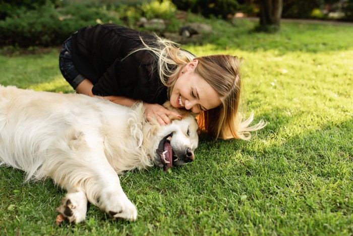 芝で戯れる犬と女性