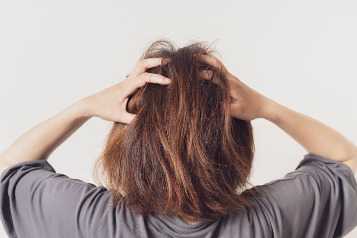 頭を抱える女性の後ろ姿