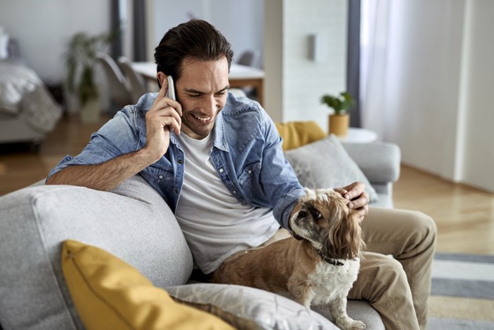 電話をしている男性と犬