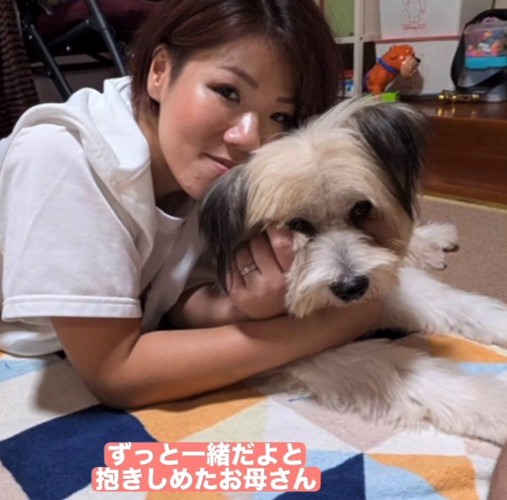 お母さんに抱きしめられている犬