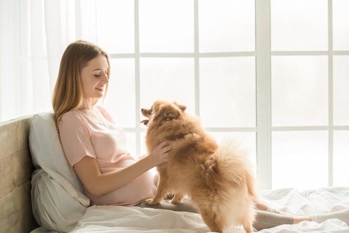 ベッドでくつろぐ女性と犬