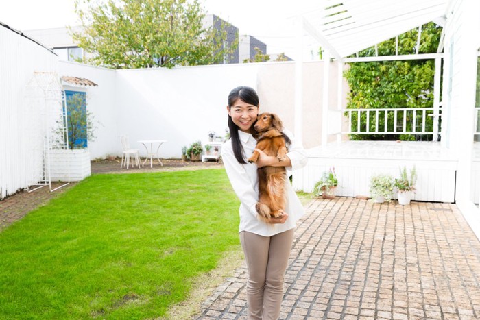 芝生のある庭と犬を抱く女性