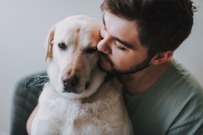 犬に後ろから寄り添う男性