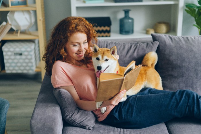 本を読みながら犬を撫でる女性