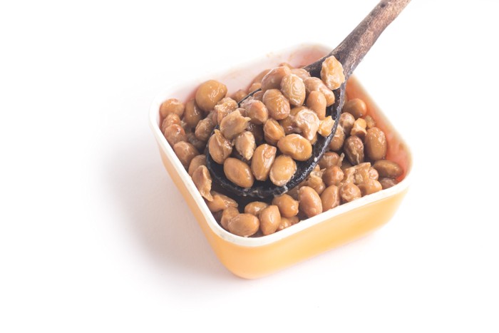小皿から納豆をスプーンですくっている様子