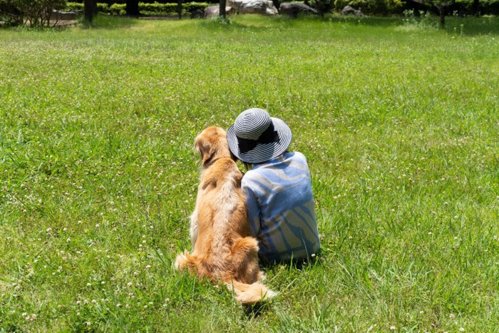 飼い主に身体をくっつけて座っている犬